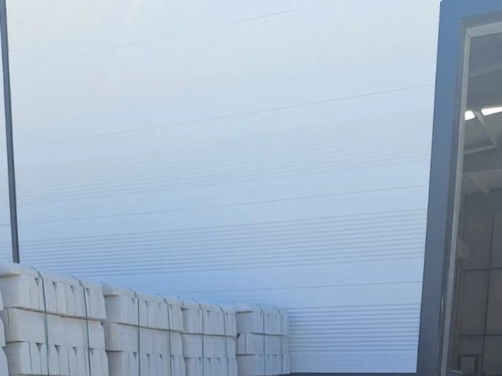 Tesis avlusunda paletlenmiş bordürler, beton çiçeklikler ve dekoratif figürler